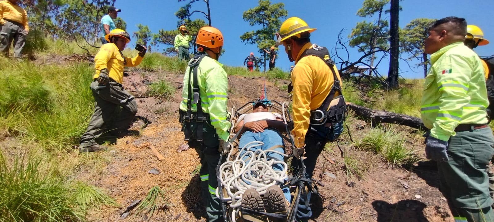 Un equipo de rescate traslada a una persona en camilla sobre una ladera